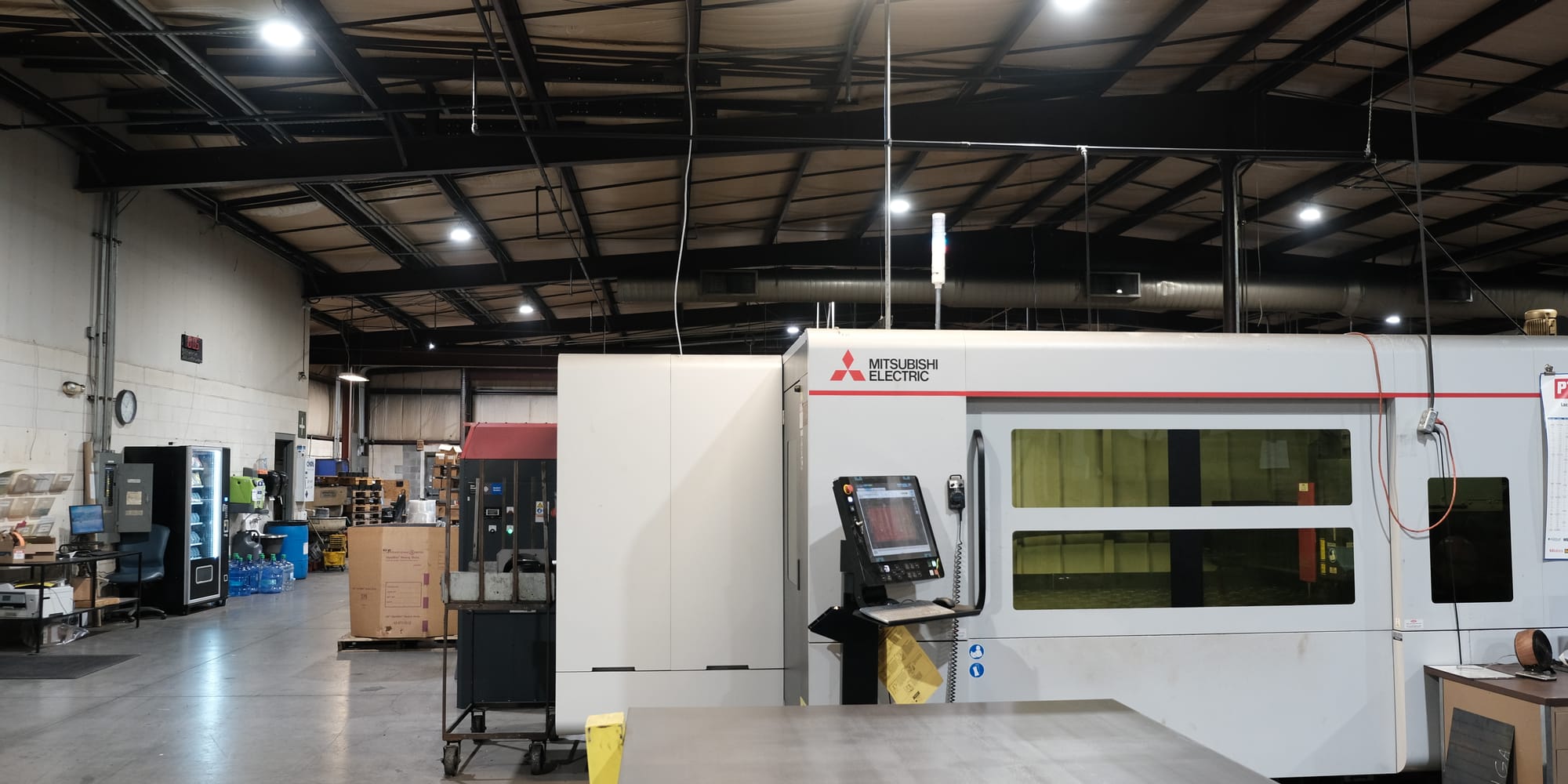 The shop floor at Advanced Tool & Machine — Mitsubishi fiber laser in the foreground